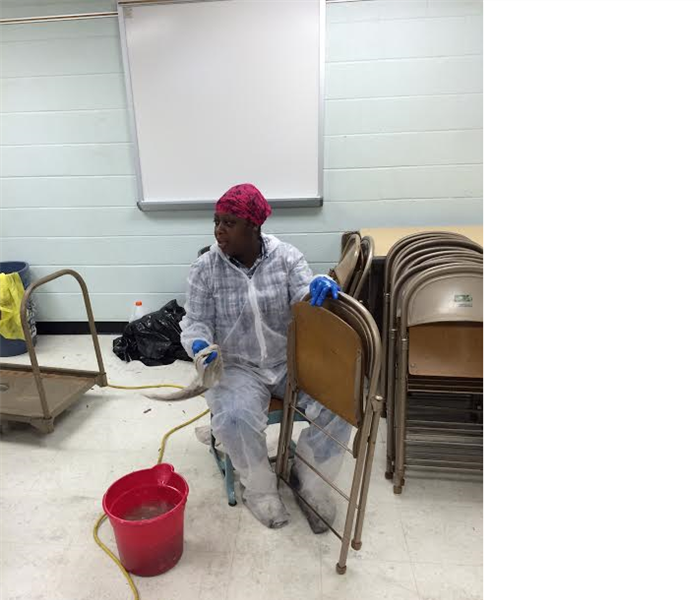 employee in PPE cleaning folding chairs