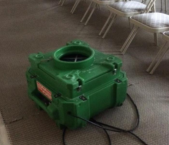 green air scrubber sitting on a brown carpeted floor